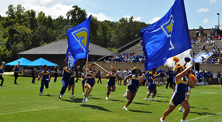 Cheerleaders running with banner flags